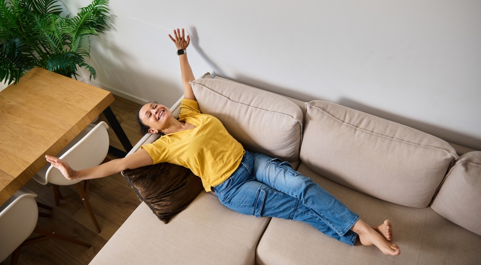 Frau streckt sich auf beigen Sofa