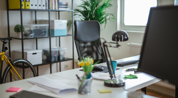 Moderner Arbeitsplatz mit Bürostuhl, Schreibtisch und Regalwand.
