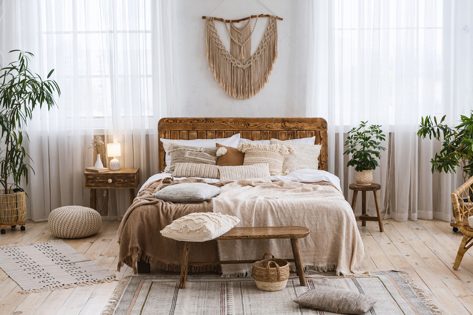 Helles Schlafzimmer im Boho-Stil mit Holzdetails, Makramee-Deko und vielen Kissen.