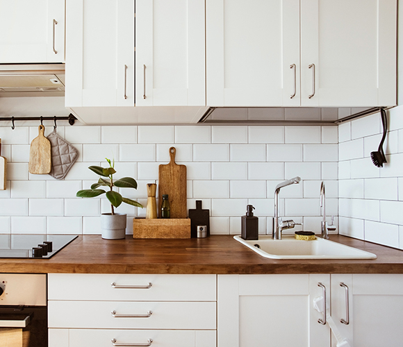 Moderne Einbauküche mit Kochfeld, Spüle und dekorativen Küchenutensilien.