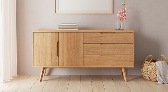 Kommode mit schrägen Beinen aus hellem Holz in einem hellen Raum