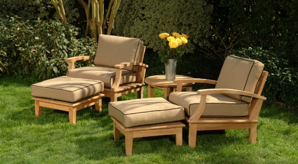 Zwei Outdoor Loungesessel aus Holz mit passenden Fu&szlig;hockern und einem kleinen Beistelltisch.