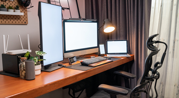 Moderner Arbeitsplatz mit mehreren Monitoren und ergonomischem Bürostuhl.