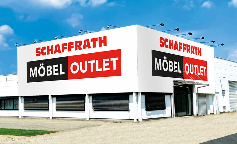 Das Bild zeigt das „Schaffrath Möbel Outlet“, ein schlichtes, weißes Gebäude mit einer modernen, klaren Fassade. Auf der oberen Ecke des Gebäudes ist ein großer Schriftzug angebracht: „SCHAFFRATH“ in roten Buchstaben, darunter „MÖBEL OUTLET“ in weißen Buchstaben auf einem schwarz-roten Hintergrund.  Der Eingangsbereich ist mit einem kleinen Vordach ausgestattet und rechts im Bild zu erkennen. Die Fenster des Gebäudes sind mit grauen Rollläden versehen. Vor dem Gebäude befindet sich eine gepflasterte Fläche, die in einen kleinen Grünstreifen übergeht. Der Himmel ist klar und blau mit wenigen dekorativen Wolken, was dem Bild eine helle und freundliche Ausstrahlung verleiht.