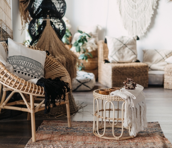 Gemütliches Boho-Wohnzimmer mit Rattansessel, Teppich, Makramee und Kissen
