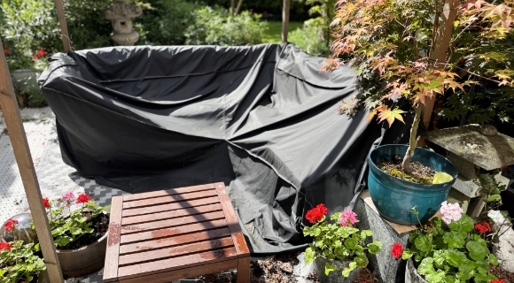 Eine Lounge-Ecke wurde zum Teil mit einer Wetterschutzh&uuml;lle versehen. Der Tisch wurde nicht abgedeckt und ist nass.