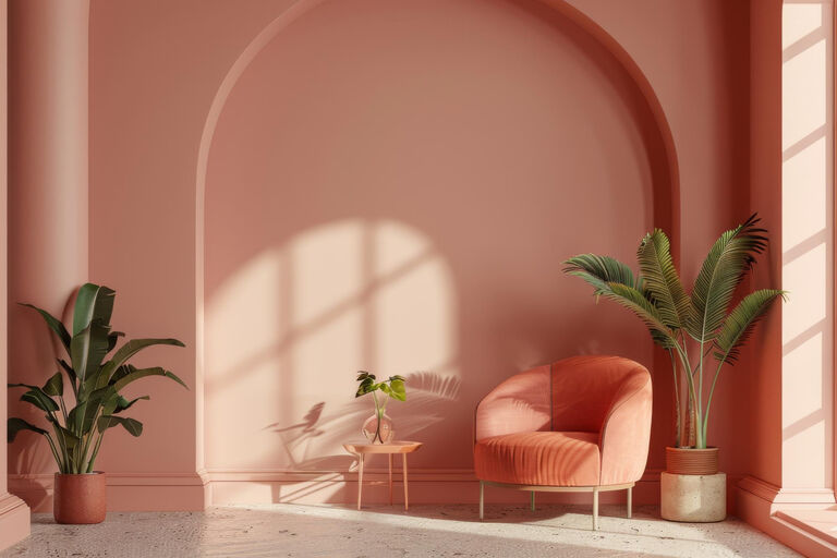 Modern eingerichteter Raum. Die Wand ist rosa gestrichen. Vor der Wand steht ein rosa Sessel und in den Ecken stehen dekorative Pflanzen.