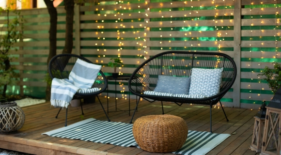 Gartenhocker steht vor einem modernen Loungeset auf einer Holz Terrasse.