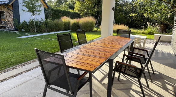 Ein ausziehbarer Tisch mit passenden St&uuml;hlen steht auf der Terrasse.