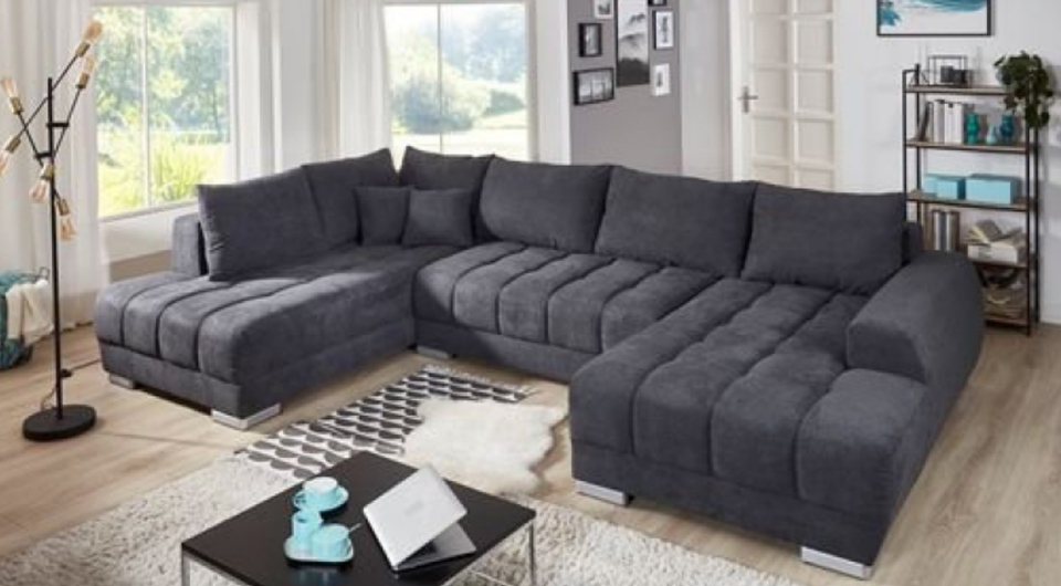 dunkelgraues Sofa in U-Form in einem modernen, hellen Wohnzimmer