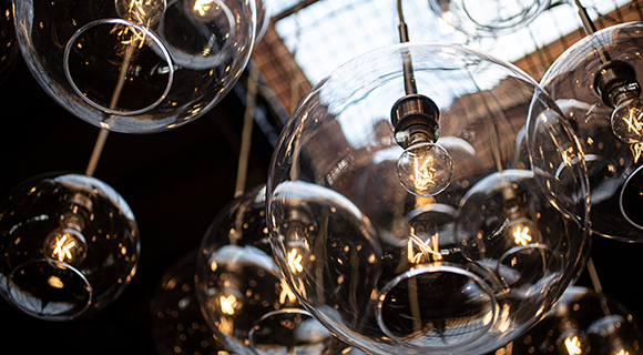 Mehrere runde Glas-Deckenleuchten mit sichtbaren Glühbirnen hängen von der Decke in einem Raum mit Dachfenster.