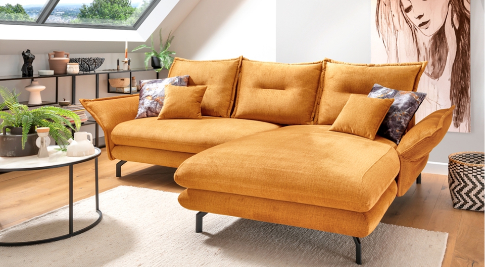 großes senfgelbes Sofa in L-Form in einem Wohnzimmer mit Dachfenster