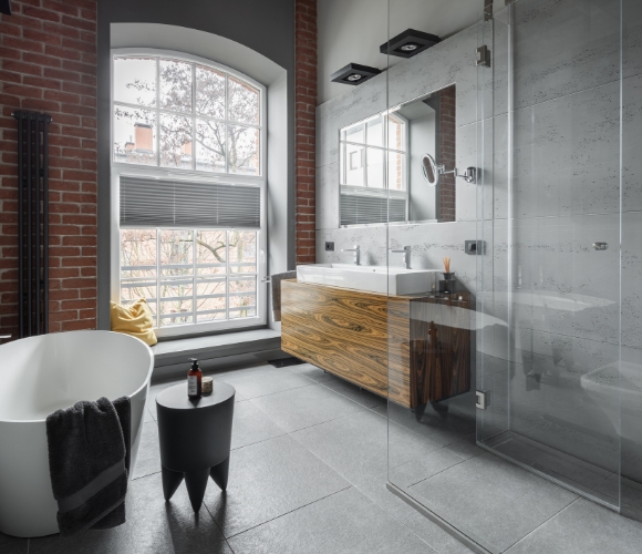 Badezimmer im Industrial Style mit freistehender Badewanne, Sichtbeton und Backsteinwand