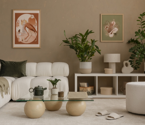 Gemütlich eingerichtetes Wohnzimmer in Beige-Tönen. Ein cremefarbenes Sofa und ein Holz-Sideboard stehen vor einer Wand.