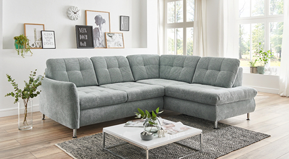 graues Sofa in L-Form in einem hellen Wohnzimmer