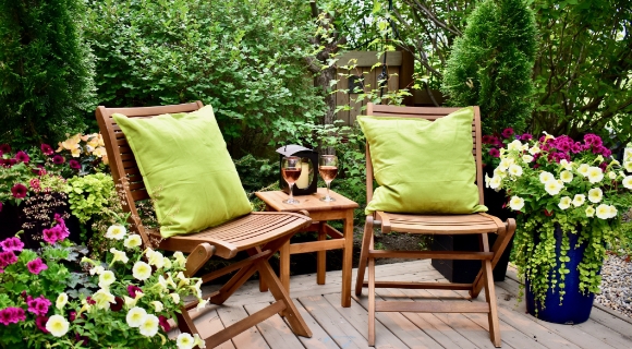 Eine Gartenterrasse mit Loungesesseln aus Holz und gr&uuml;nen Kissen.