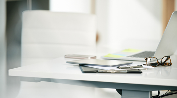 Nahaufnahme eines minimalistischen Bürotisches mit Arbeitsutensilien in professioneller Umgebung.