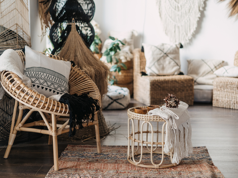 Gemütliches Boho-Wohnzimmer mit Rattansessel, Teppich, Makramee und Kissen