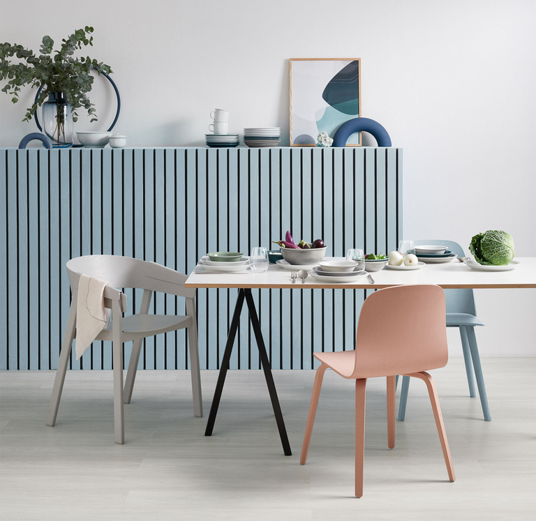 Moderner Essplatz mit pastellfarbenen Stühlen, gedecktem Tisch und blauer Wandverkleidung.