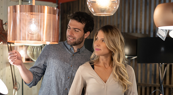 Zwei Personen betrachten verschiedene Lampen und Deckenleuchten in einem Beleuchtungsgeschäft.