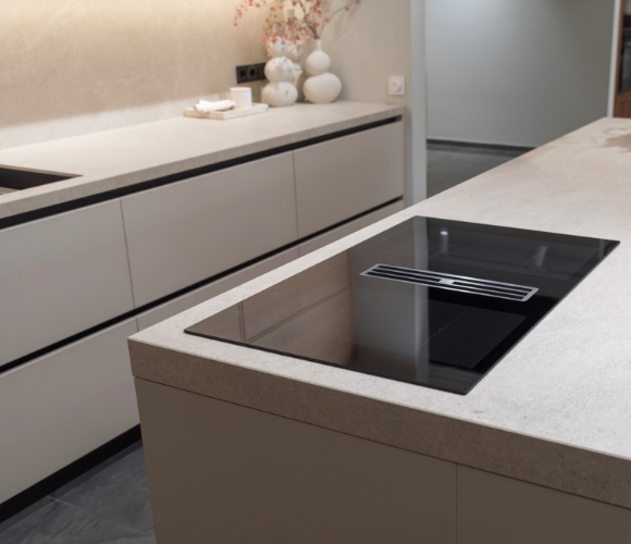 Detailaufnahme einer K&uuml;cheninsel mit modernem Induktionskochfeld und integrierter Abluftanlage in minimalistischer K&uuml;che