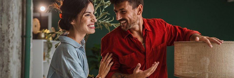 Paar in gemütlicher Wohnung mit grüner Wand und Stofflampe im skandinavischen Einrichtungsstil.
