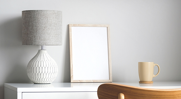 Dekorative Tischszene mit großer Keramiklampe, Holzrahmen und einer Kaffeetasse.