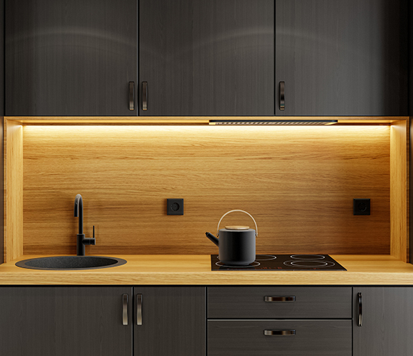 Moderne Küche mit schwarzen Schrankfronten, Holzarbeitsplatte und LED-beleuchteter Rückwand.