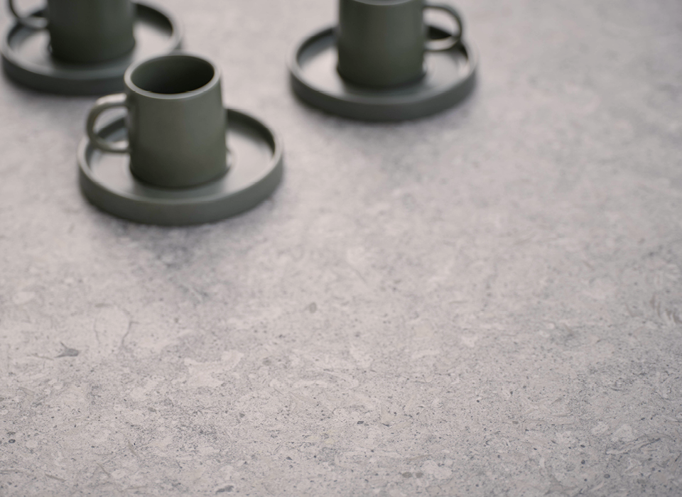 Detailanischt einer Keramik Tischplatte, auf der drei dunkelgr&uuml;ne Tassen mit Untertasse dekorativ platziert sind