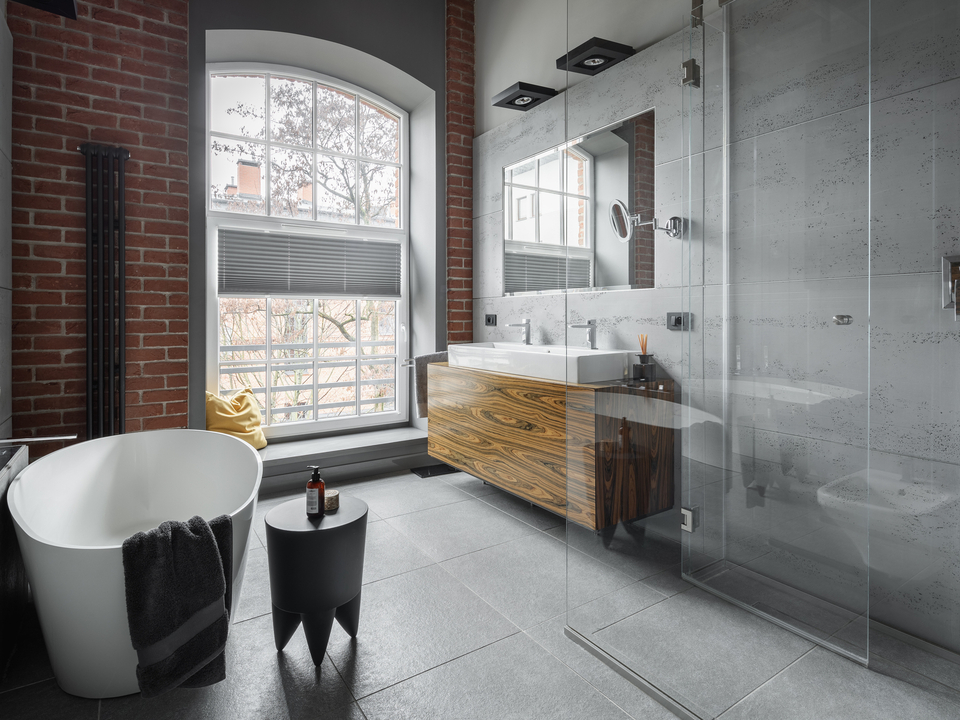 Badezimmer im Industrial Style mit freistehender Badewanne, Sichtbeton und Backsteinwand