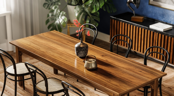 Rechteckiger Holztisch mit sechs schwarz gerahmten Stühlen auf Holzfußboden; auf dem Tisch stehen zwei Vasen mit Blumen und Kerze, im Hintergrund große Zimmerpflanze, Sideboard mit Lamellenfront und Grammofon.