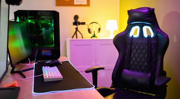 Gaming-Stuhl an Schreibtisch mit Computer und bunter Beleuchtung.