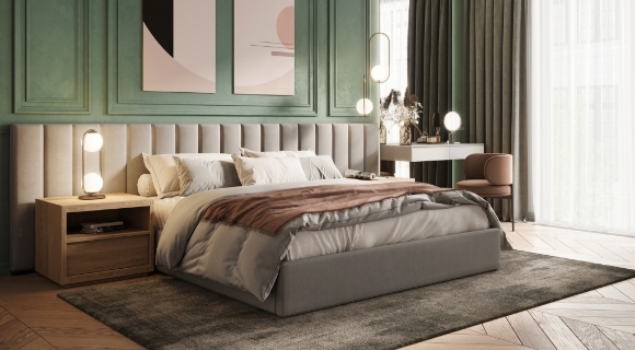 Graues Boxspringbett steht vor einer grünen Wand in einem modern eingerichteten Schlafzimmer. 