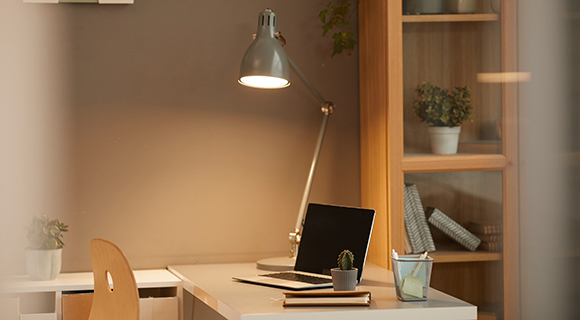 Moderne Schreibtischlampe aus Metall beleuchtet Arbeitsplatz im Homeoffice.