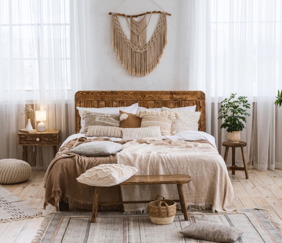 Helles Schlafzimmer im Boho-Stil mit Holzdetails, Makramee-Deko und vielen Kissen.