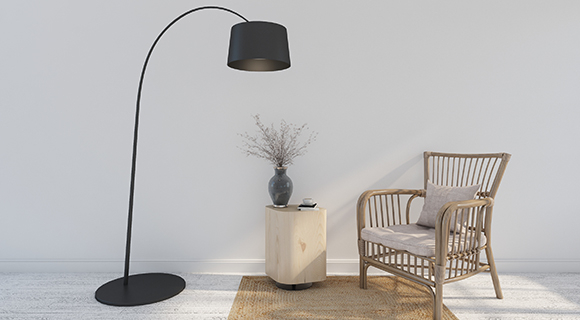 Heller Wohnbereich mit schwarzer Bogenlampe, Holzstuhl mit Kissen und kleinem Beistelltisch auf Teppich.