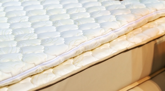 Detailansicht eines beigen Boxspringbetts mit sichtbarem Matratzenaufbau und Topper
