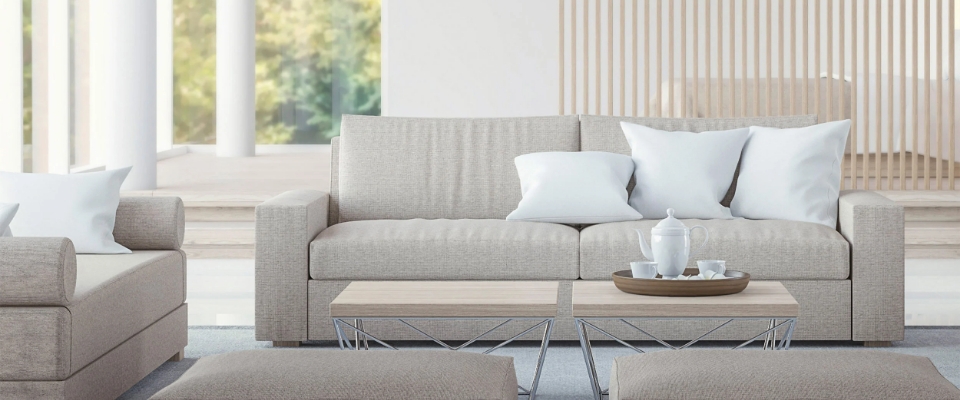 Helles, monochrom gehaltenes Wohnzimmer mit beigen Sofas, runden Couchtischen und moderner Deckenleuchte.
