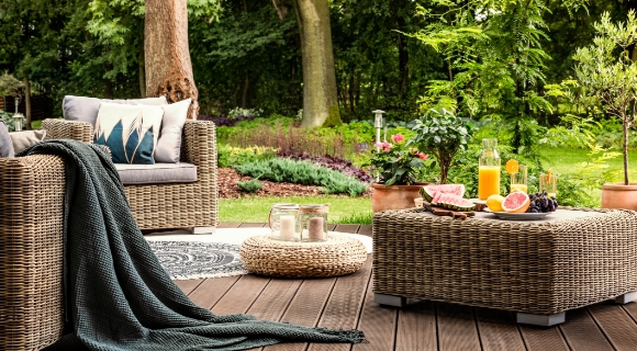 Rattan-Loungesessel mit einem passenden Tisch und verschiedenen Deko-Elementen.
