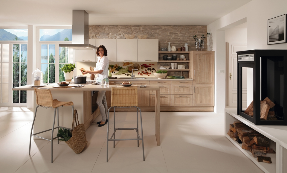 Landhausküche mit Creme- und Holzfarben mit Frau, die am Herd steht.