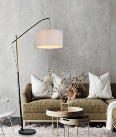 Sofa mit dekorativer Deko und einer modernen Stehleuchte vor einer grauen Betonwand.