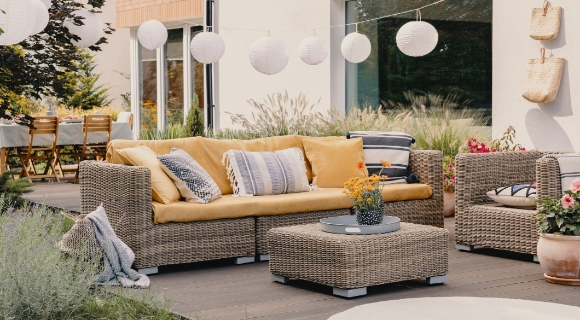 Moderne Lounge-Ecke auf der Terrasse mit Lounge-Gartentisch und weichen Kissen.