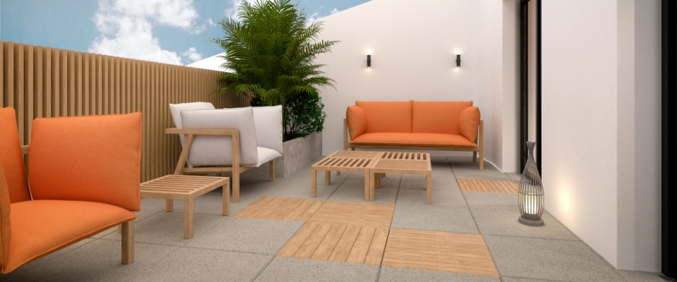Terrasse mit zwei Sofas und Sessel mit orangefarbenen Polstern, Holztischen und Steinboden vor wei&szlig;er Hauswand.