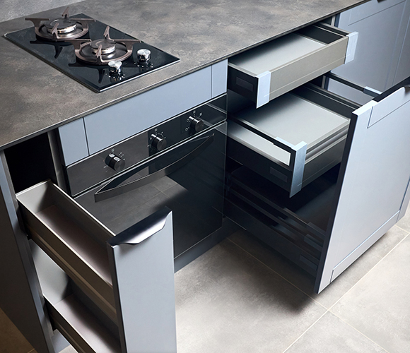 Moderne Küche mit geöffneten Schubladen, Gasherd und Backofen in grauen Fronten.