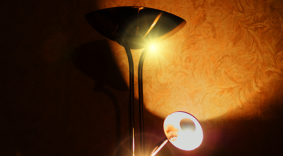 Moderne Doppelstehlampe mit direktem und indirektem Licht vor gemusterter Wandtapete.