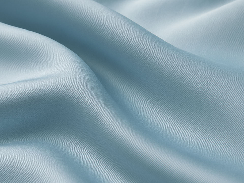 Nahaufnahme eines fließenden, hellblauen Satin-Stoffs mit glänzender Oberfläche und feiner Webstruktur