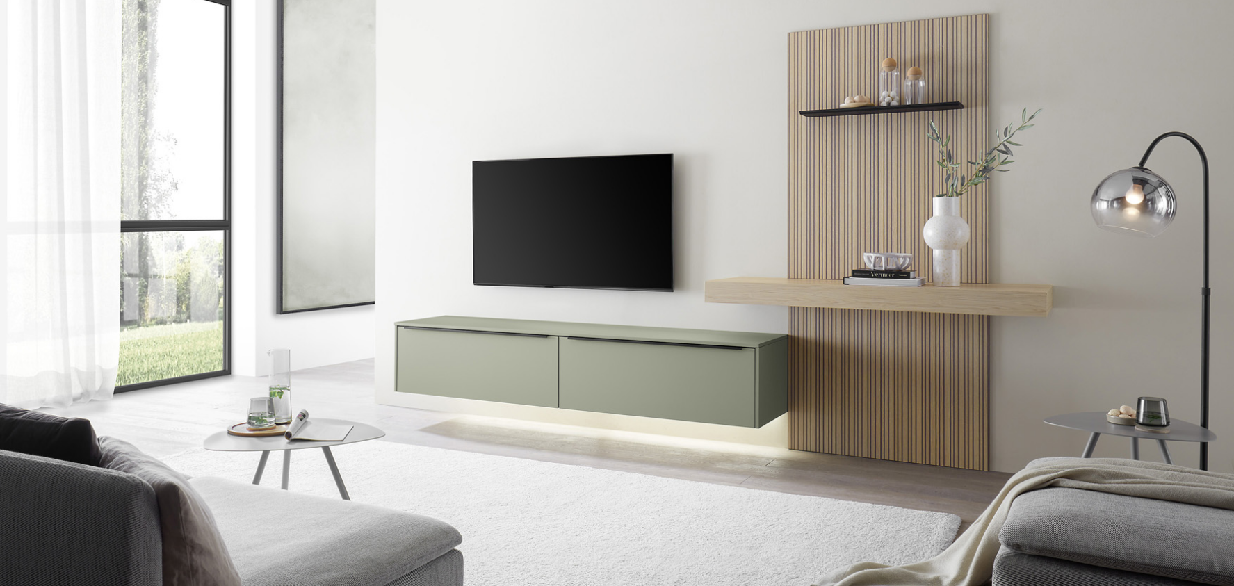 Modernes, salbeigr&uuml;nfarbenes Sideboard von Mondo mit Holzelementen, welches in einem hellen, offenen Wohnzimmer an einer wei&szlig;en Wand steht.