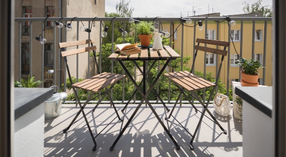 Zwei Klappst&uuml;hle und ein kleiner Klapptisch stehen auf einem Balkon in der  Stadt
