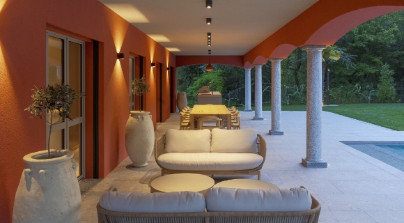 Moderne Terrasse mit Loungem&ouml;beln, langem Esstisch, S&auml;ulenarchitektur und angrenzendem Pool.