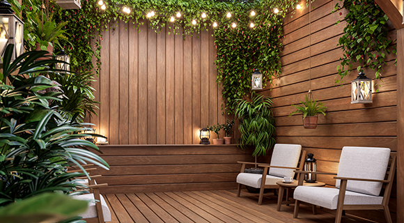 Gemütliche Holzterrasse mit Sitzbereich, Hängepflanzen und stimmungsvoller Beleuchtung.